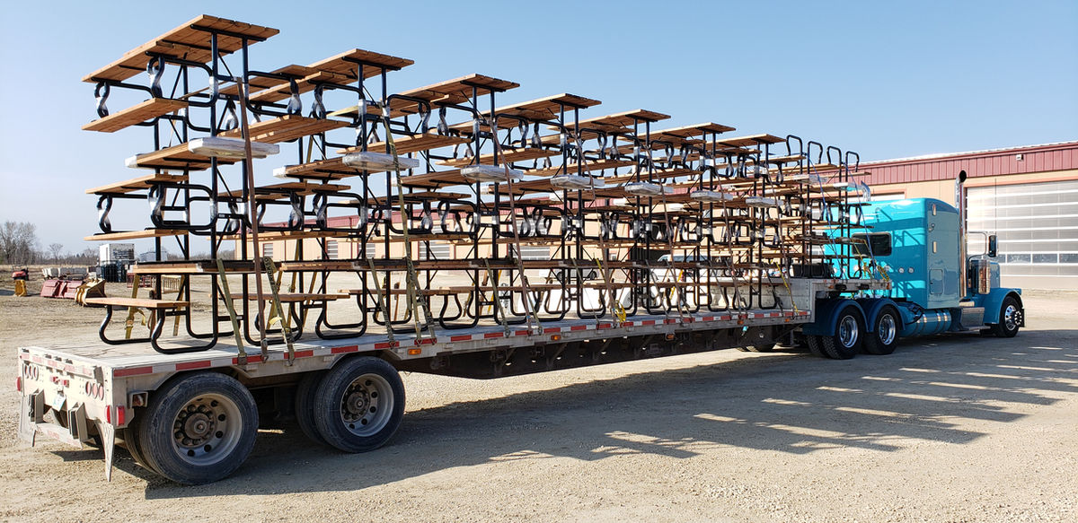 Flatbed truck loaded with steel picnic tables