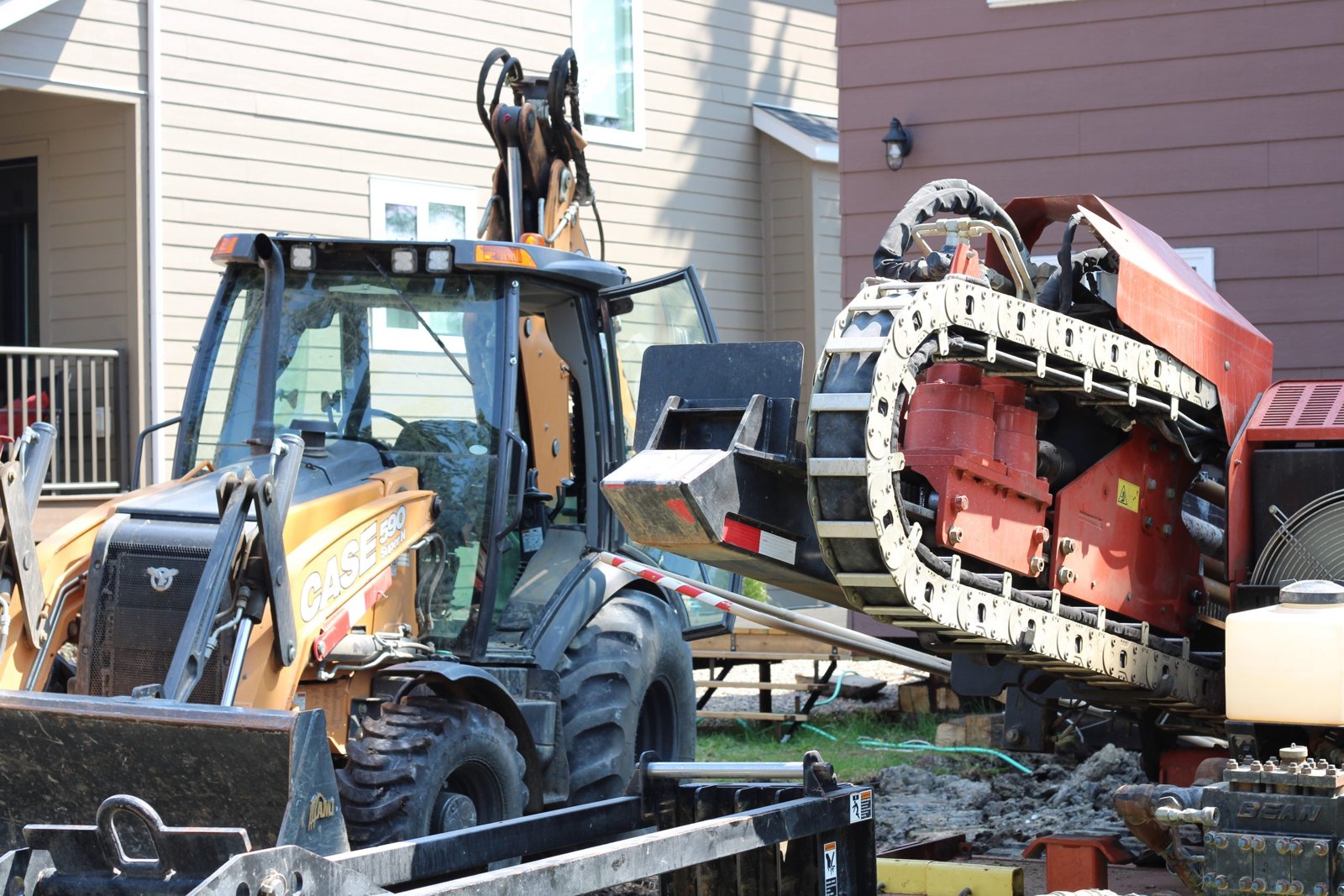 Backhoe and directional drill beside a house
