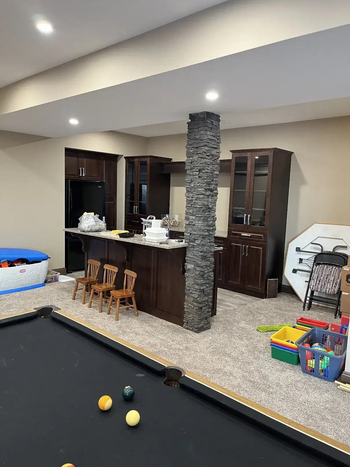 Basement bar and kitchenette with custom dark wood cabinetry
