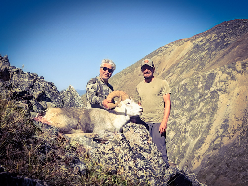Hunters with a Stone sheep ram on a mountain ridge