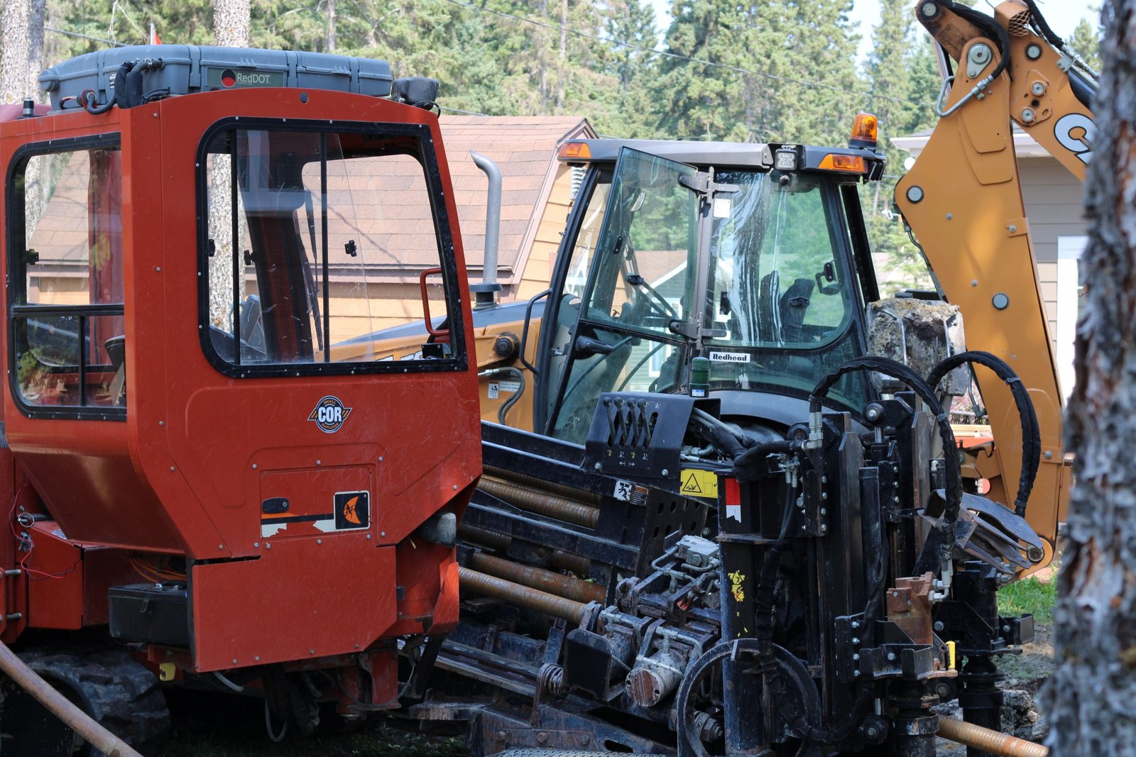 Red directional drill rig and backhoe