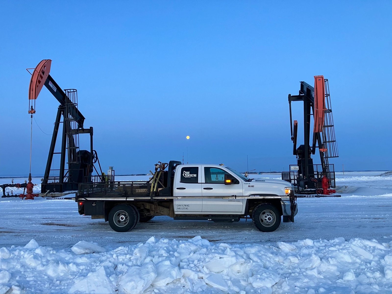 Dire Contracting flat-deck truck at a pumpjack site in Alberta