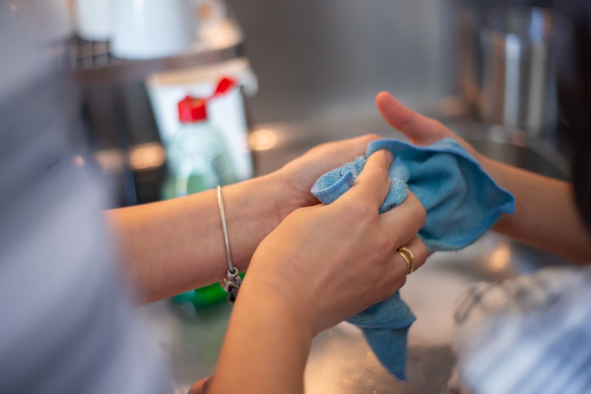 Hands wiping a kitchen counter with a cloth
