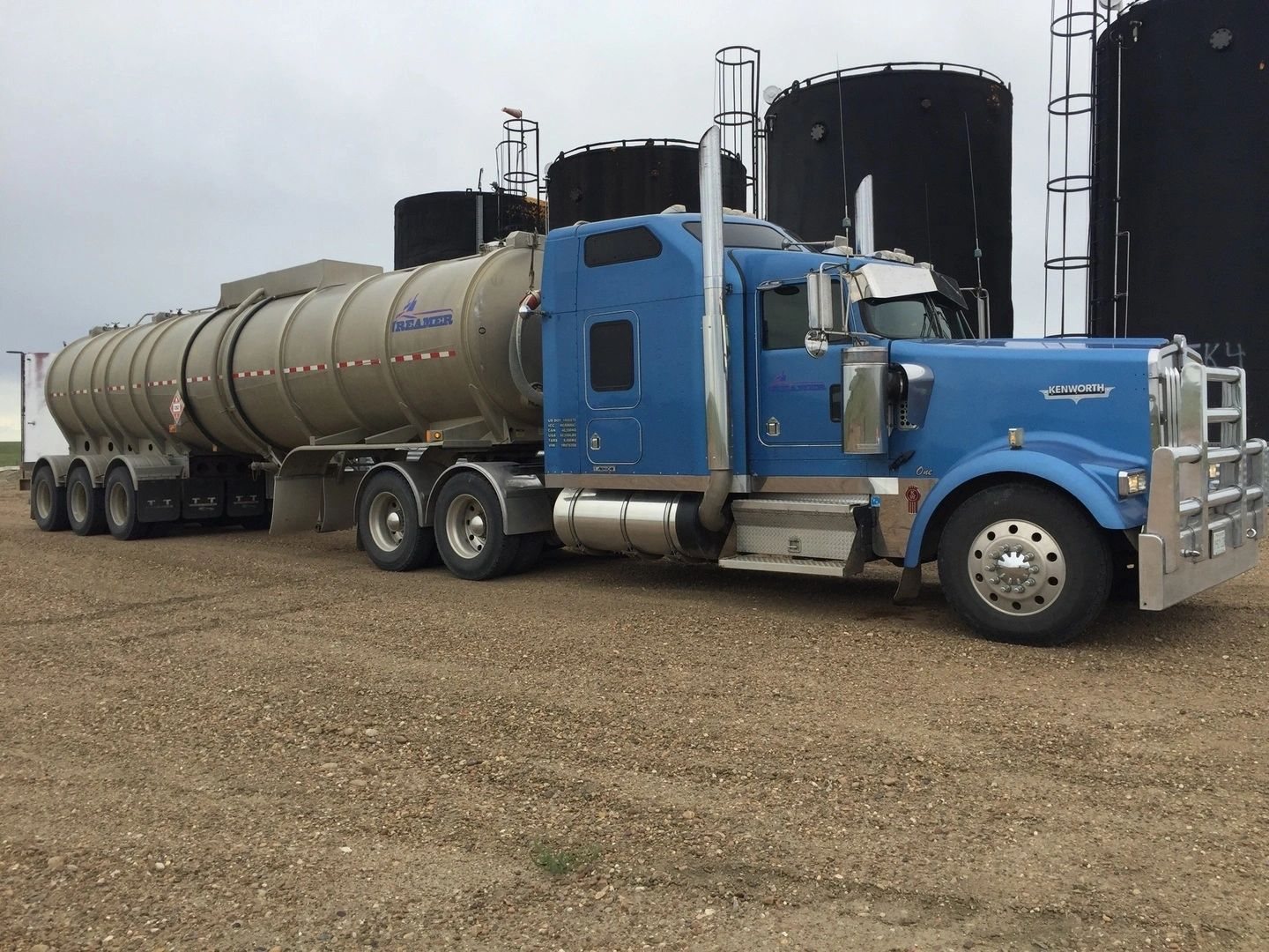 Blue Kenworth with Reamer tanker trailer at an oilfield site