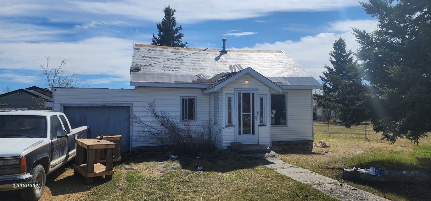 Roof tear-off with new underlayment on a white-sided house